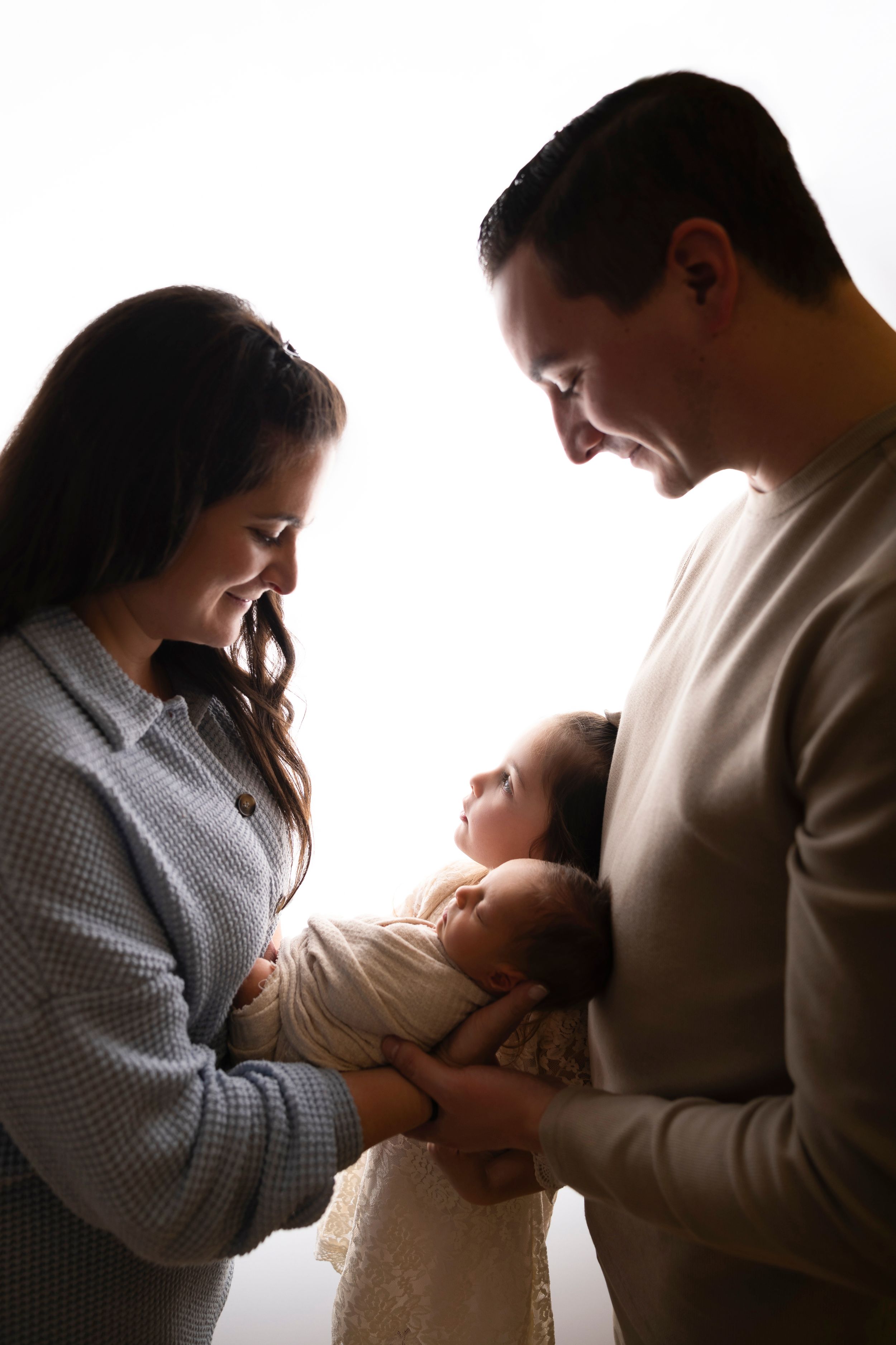 Four sequential images show tender moments between parents and their newborn baby in soft, intimate lighting.