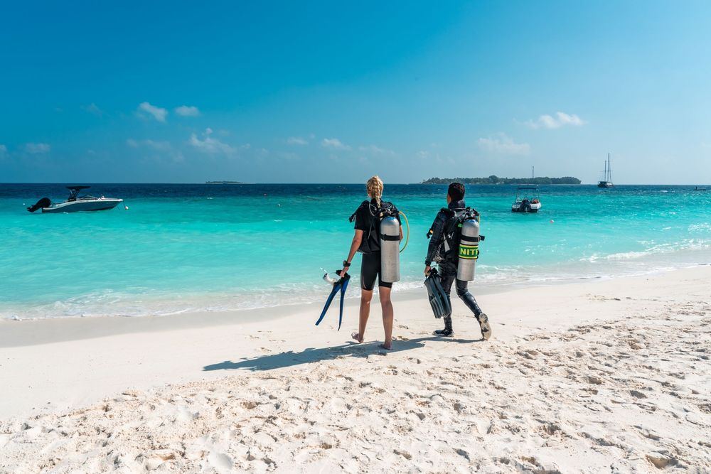 Panoramic view of a pristine white sand beach with crystal clear turquoise waters and boats in the distance.