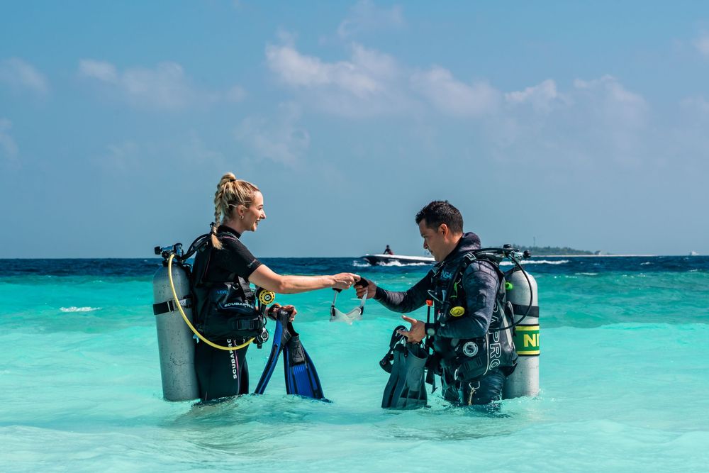 Scuba diving instructor teaches students proper diving techniques in crystal clear turquoise Caribbean waters.