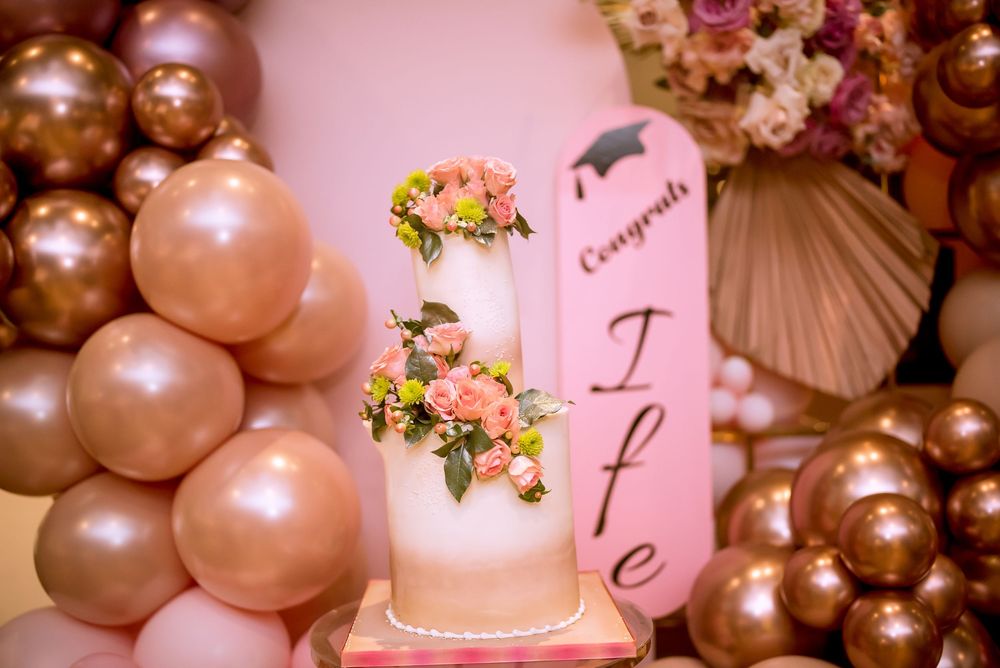 Pink and gold balloon arch decorations with elegant floral accents create a romantic party atmosphere.