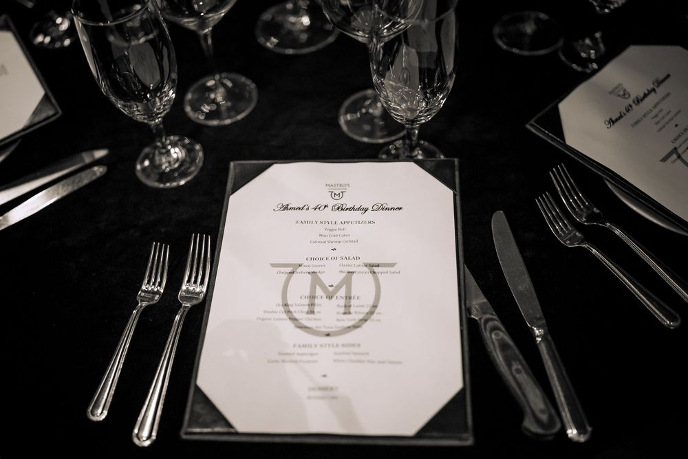 Elegant black and white table settings with menus and wine glasses at a formal dining event.