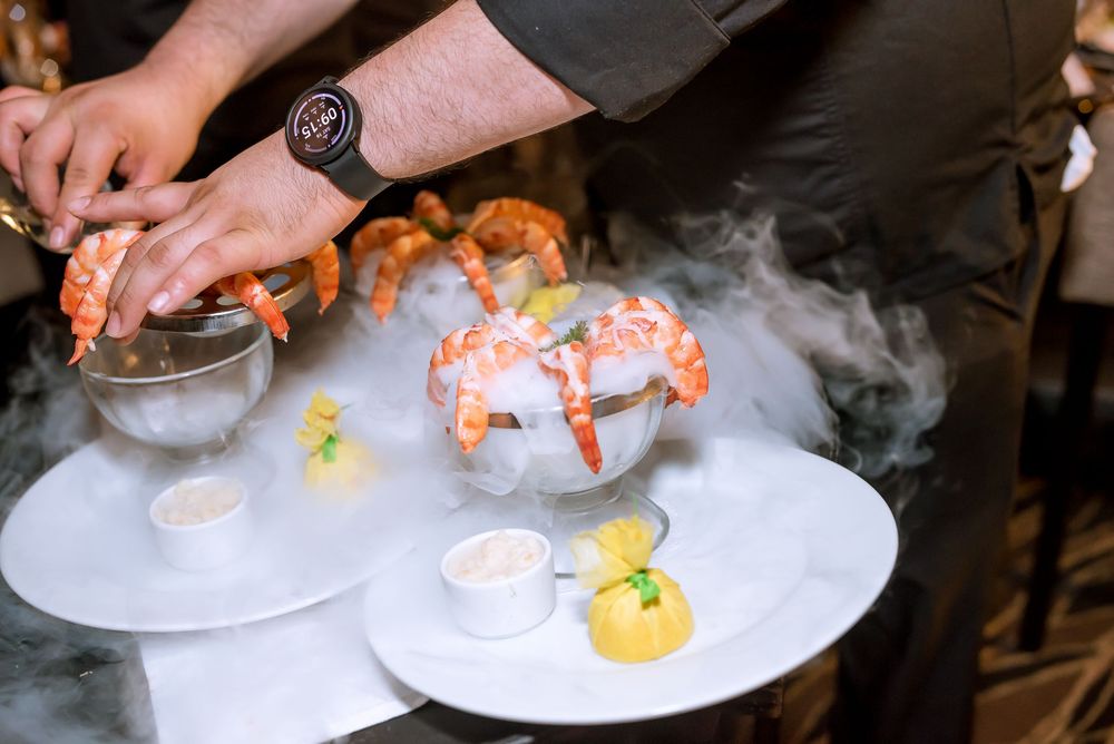 Chef plates gourmet lobster dish with delicate garnishes on white plates in restaurant kitchen.