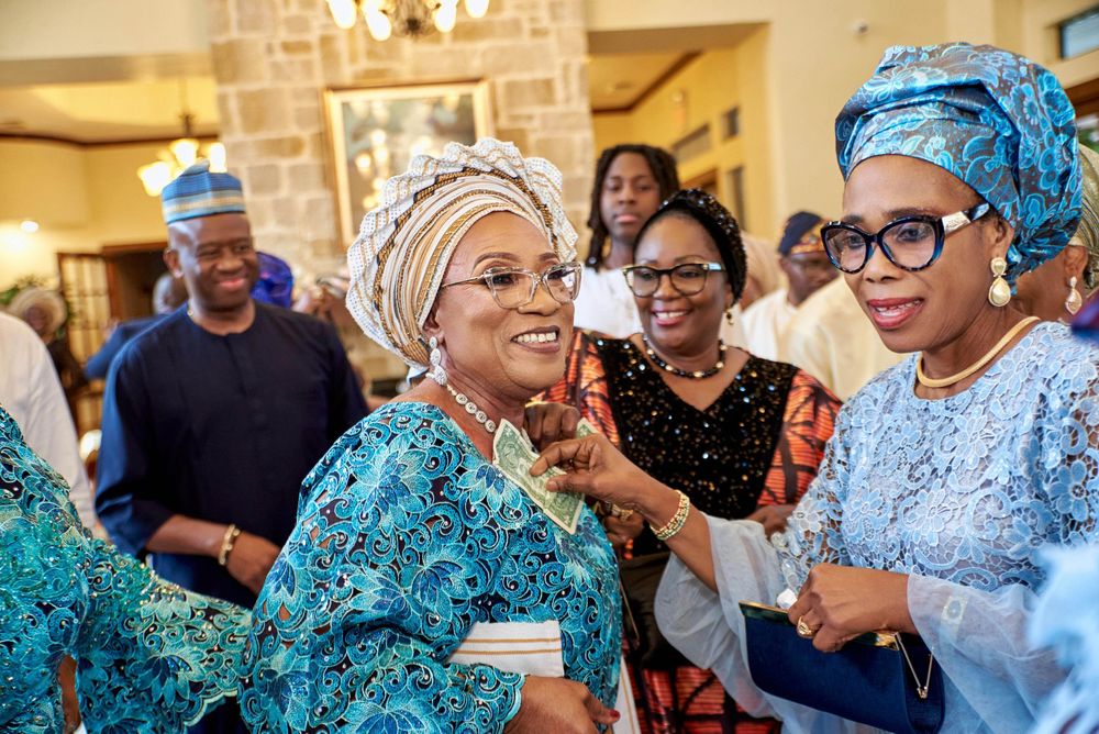 A group of people in traditional blue and white attire celebrate joyfully at an indoor gathering.