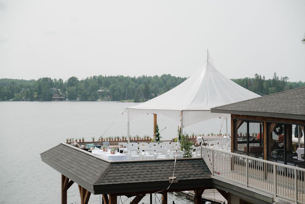 White tent and covered dock structures along a lake with boats in the distance.