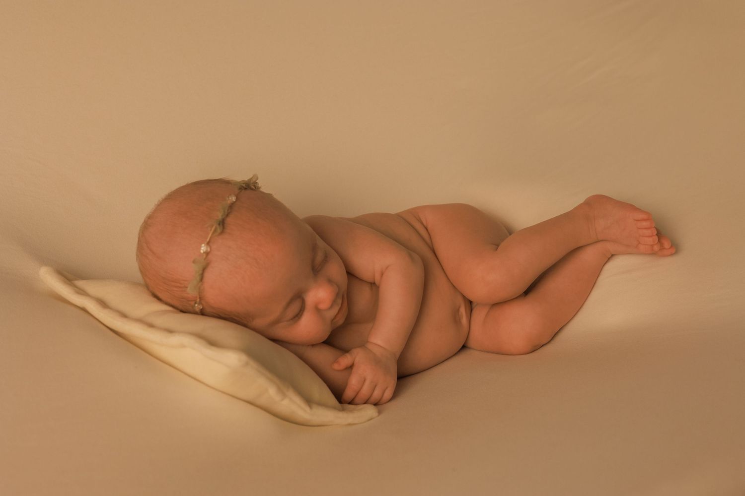 A sleeping baby lies peacefully on a cream-colored blanket in a series of connected photographs.