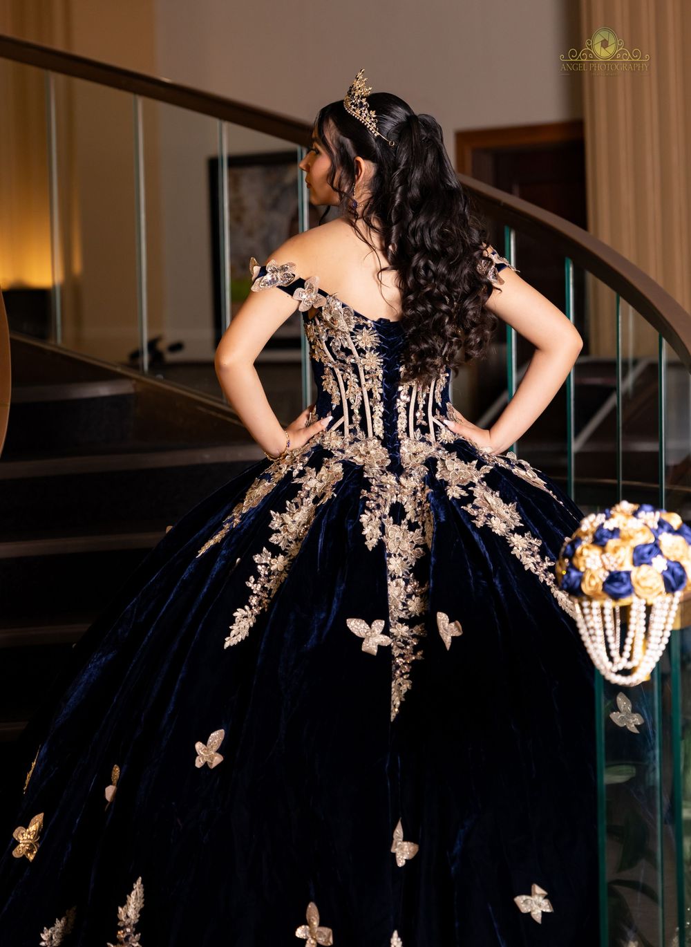 A stunning navy blue ball gown with intricate gold butterfly appliques cascades elegantly across multiple views.