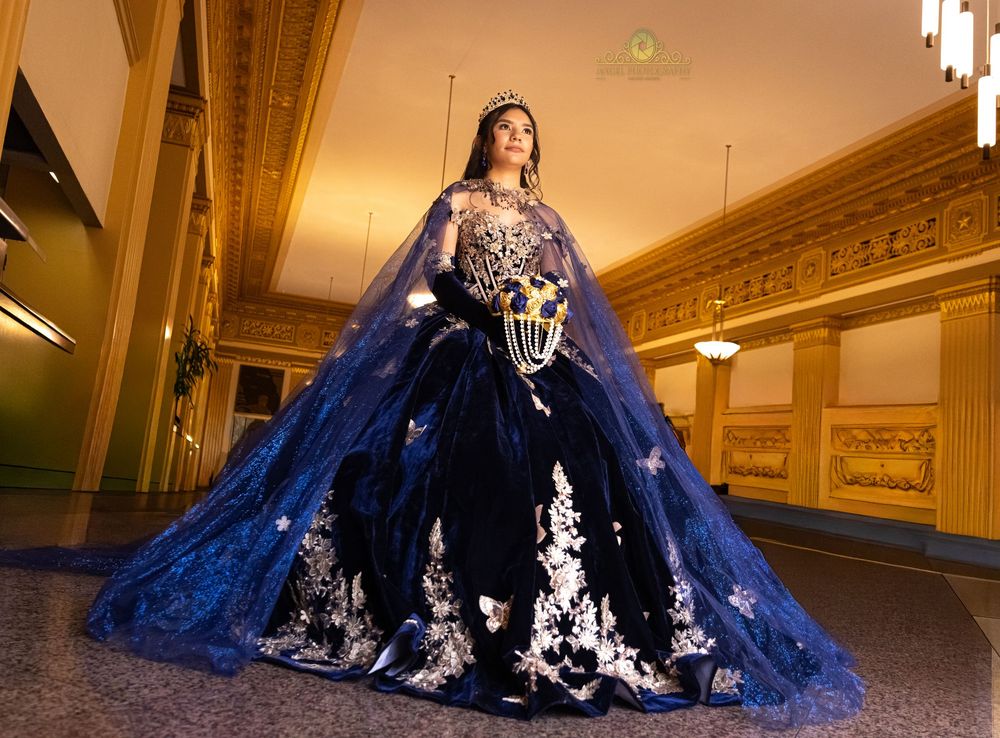 A stunning navy blue ball gown with white lace appliques flows across a luxurious ballroom floor.