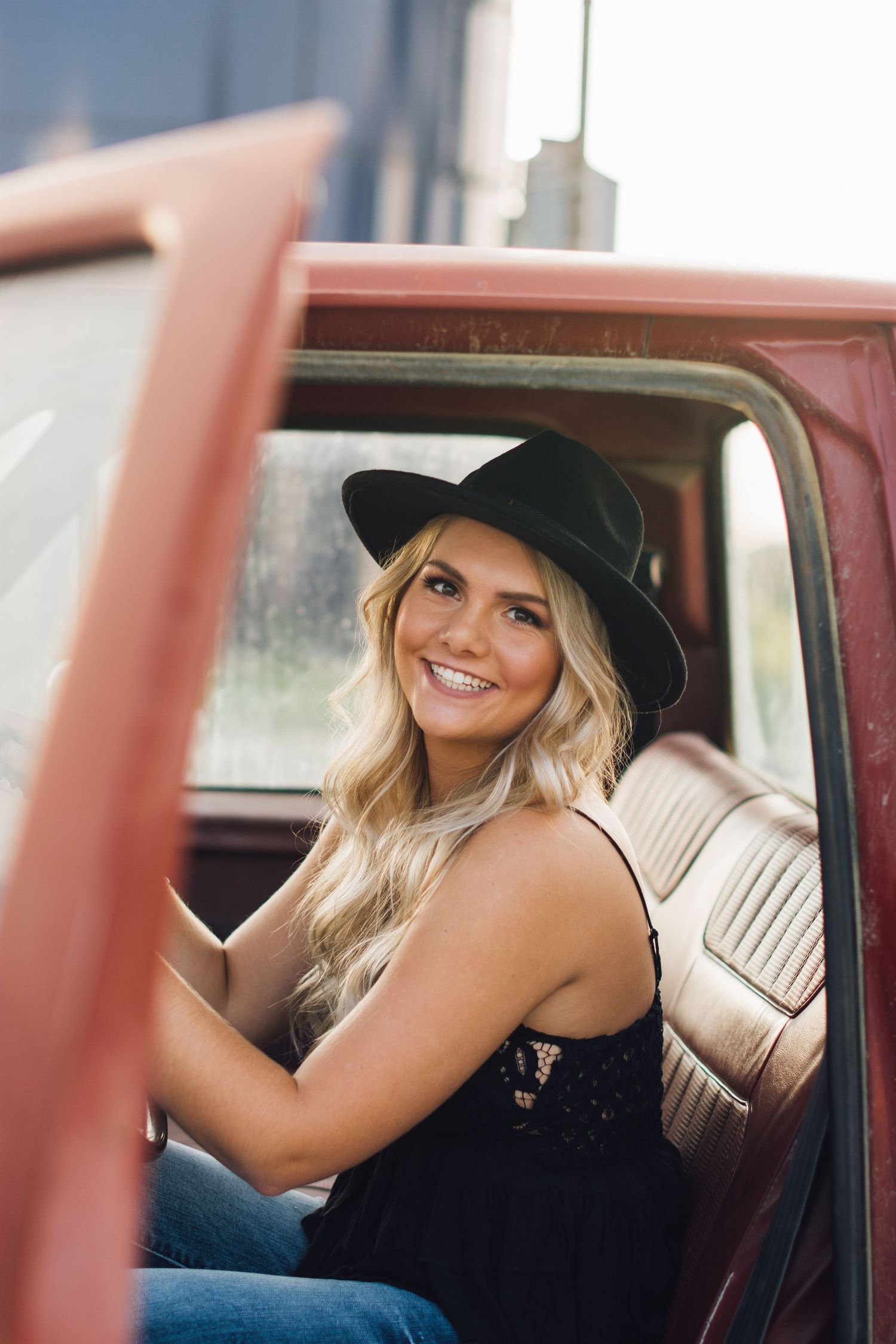 Casual portrait series inside vintage red car wearing black hat.