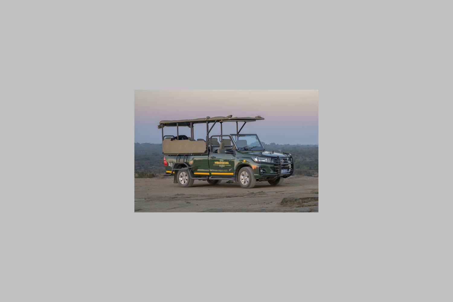A Open Safari Vehicle (OSV) parked on a hill with a hazy horizon under a soft, morning sky.