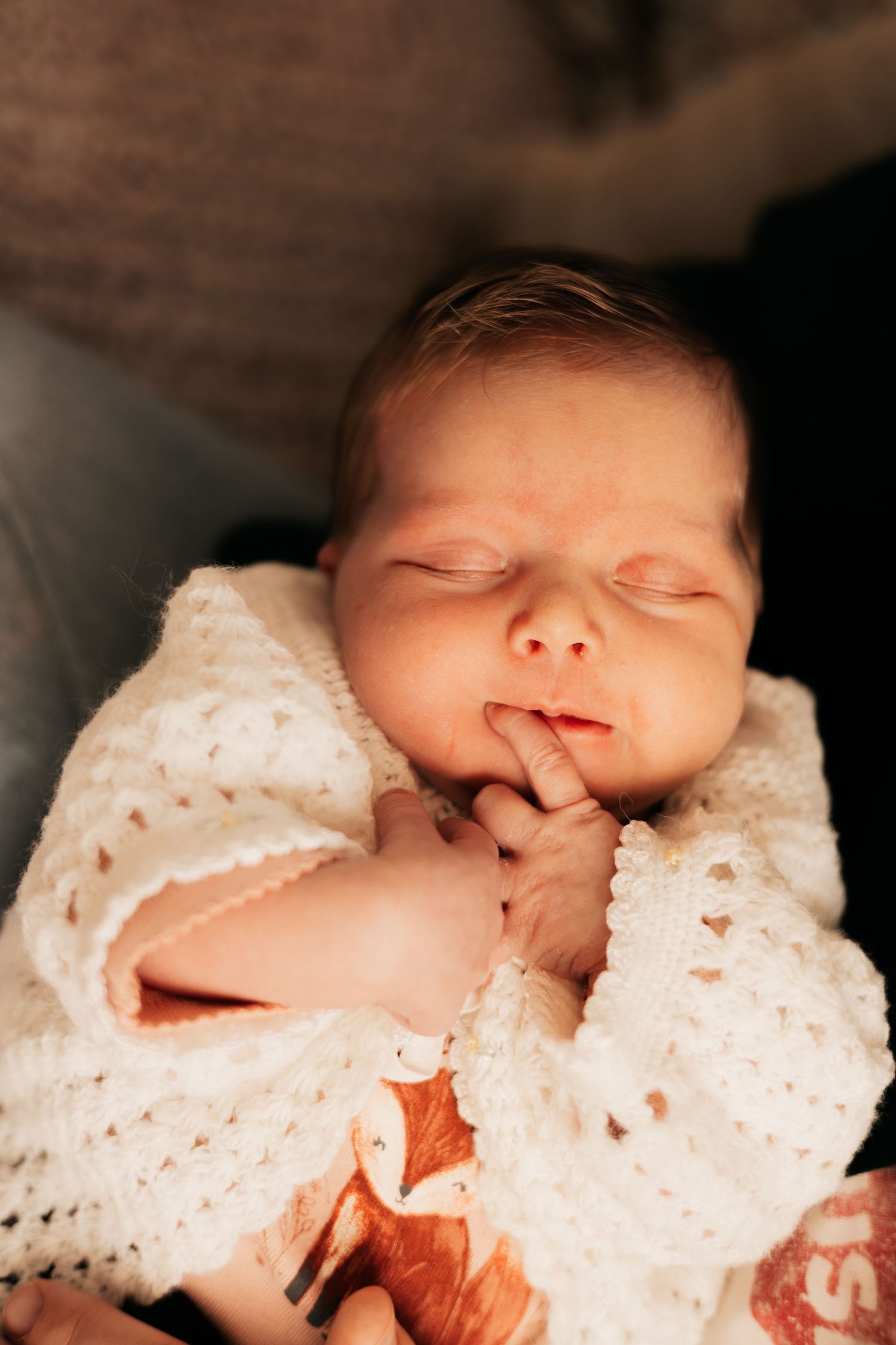 Peaceful newborn sleeping in a white crochet blanket cradled in loving arms |Newborn Photos When You Don't Feel Like Yourself