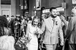 Newlyweds walk joyfully down the aisle in black and white wedding recessional photo.