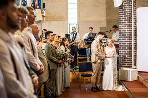 Bride and groom sharing an intimate moment at the altar surrounded by bridesmaids and wedding guests.
