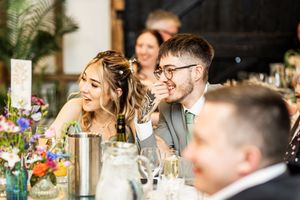 Bride and groom sharing a laugh with guests at a beautifully decorated wedding reception table.
