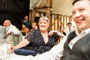 Wedding guest in polka dot dress smiling and relaxing at the reception in a barn venue.