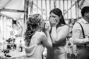 Emotional wedding moment in black and white as bride comforts tearful bridesmaid at reception venue.