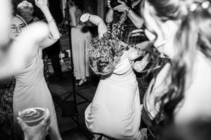 Wedding guest dances enthusiastically on crowded dance floor in candid black and white reception photograph.