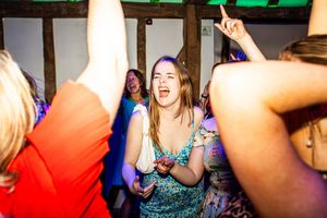 Young woman dancing energetically at a wedding reception party in a rustic barn venue.