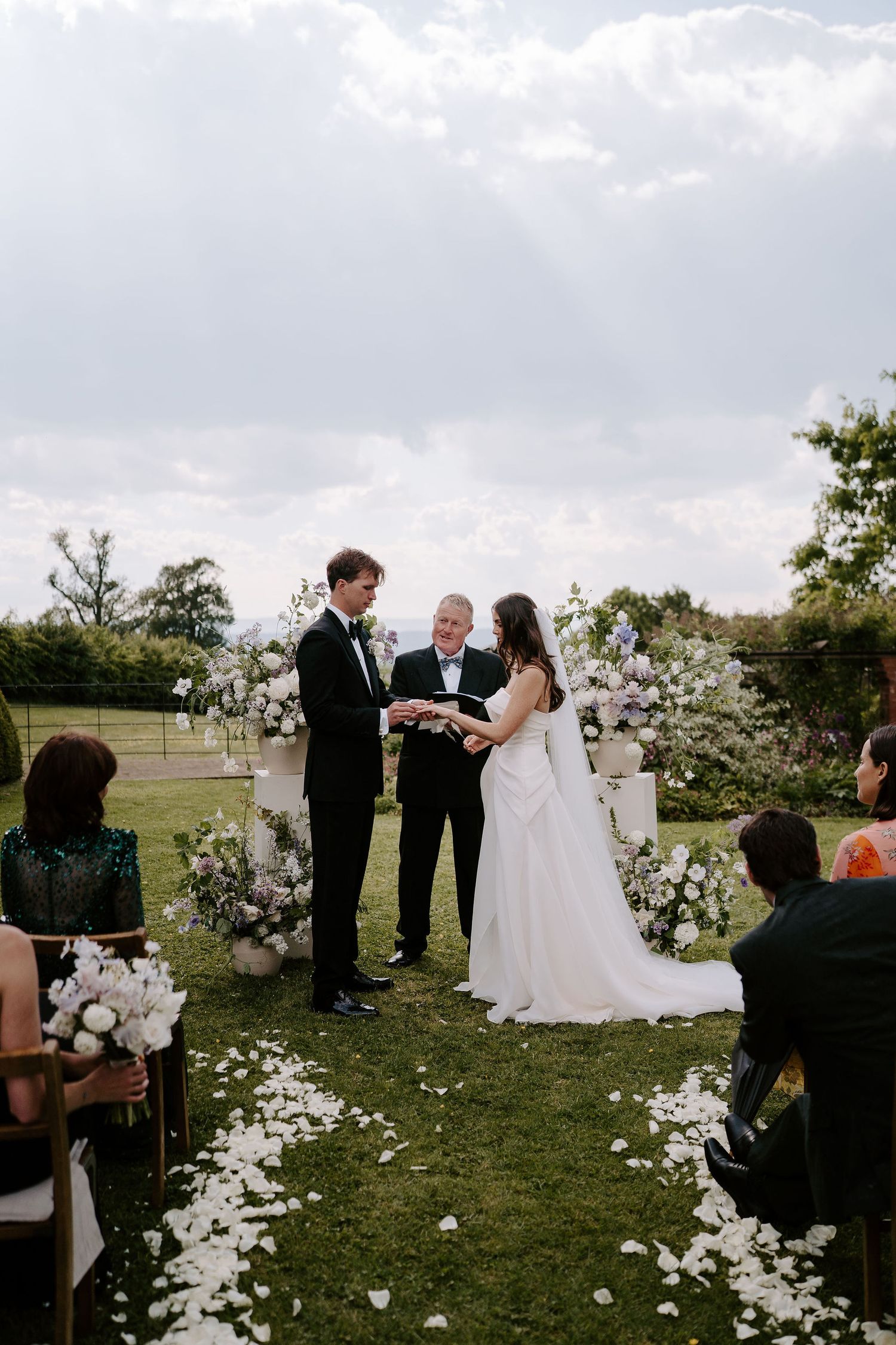 groom putting ring on brides finger during wedding ceremony at dewsall court in herefordshire
