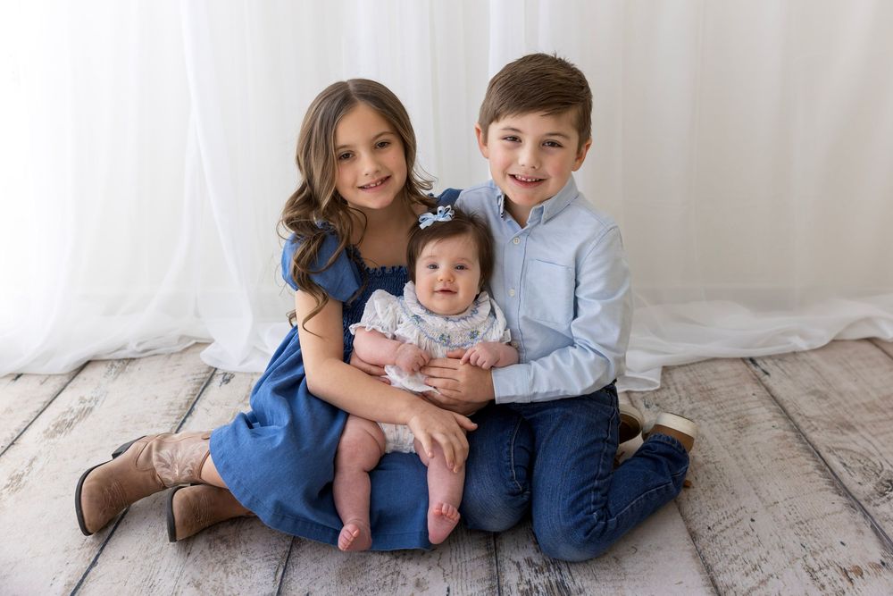 Sweet sibling posing together with baby for milestone session in Hendersonville studio.