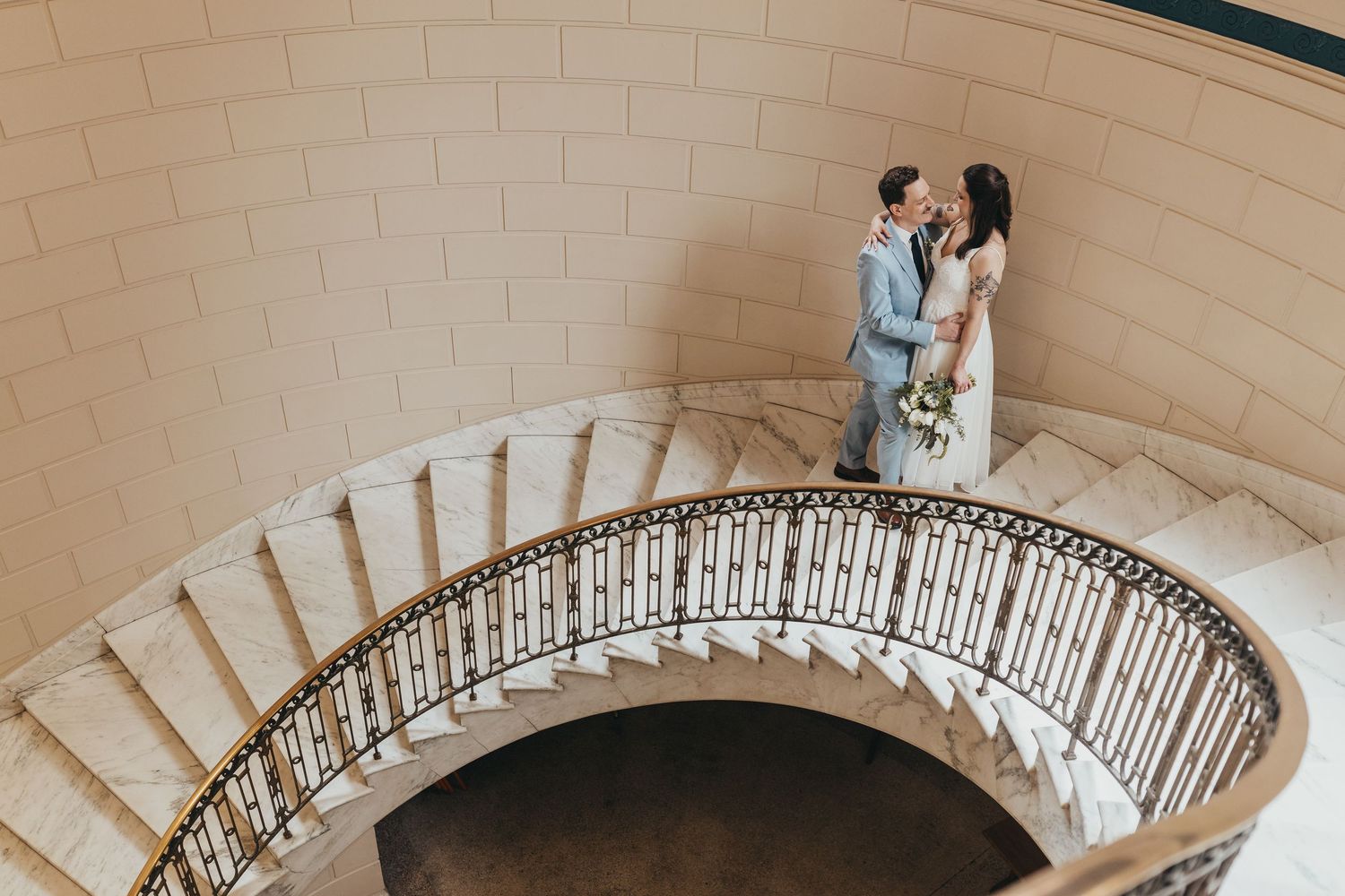 Elegant spiral staircase with ornate wrought iron railings in a light-filled space.