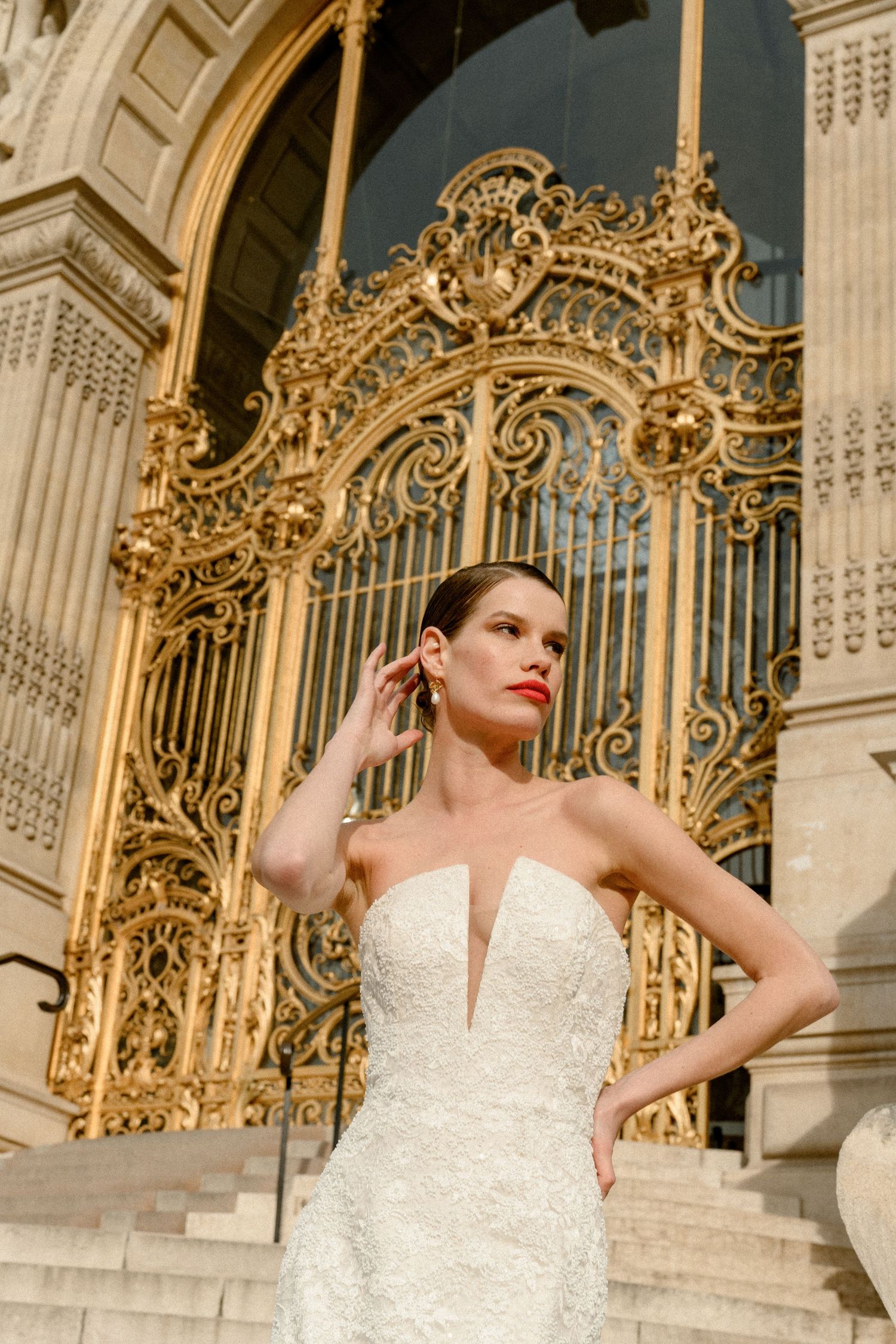 Elegant wedding dress with deep plunging neckline photographed against ornate golden baroque architectural details.