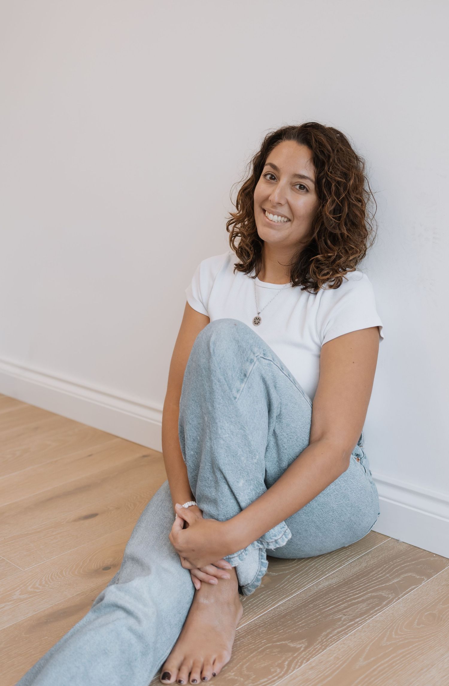 Woman in casual white t-shirt and blue pants relaxing on hardwood floor. Photography in Buckinghamshire.
