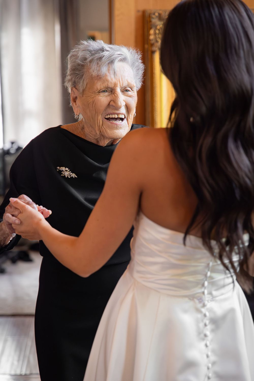 Emotional first look reaction between bride in white dress and guest in black at wedding venue.