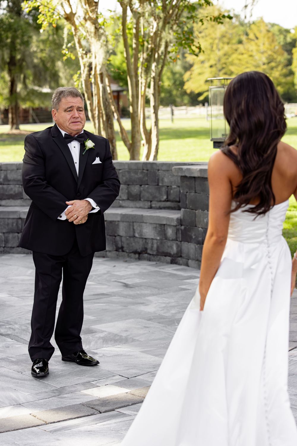 Emotional first look moment between bride and father on stone patio.