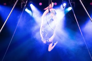 Aerial performers in blue stage lighting create a dramatic silhouette during a circus performance.