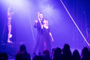 Performers on stage bathed in dramatic purple lighting during a concert performance.