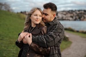 A romantic couple embraces while walking along a coastal path during sunset.