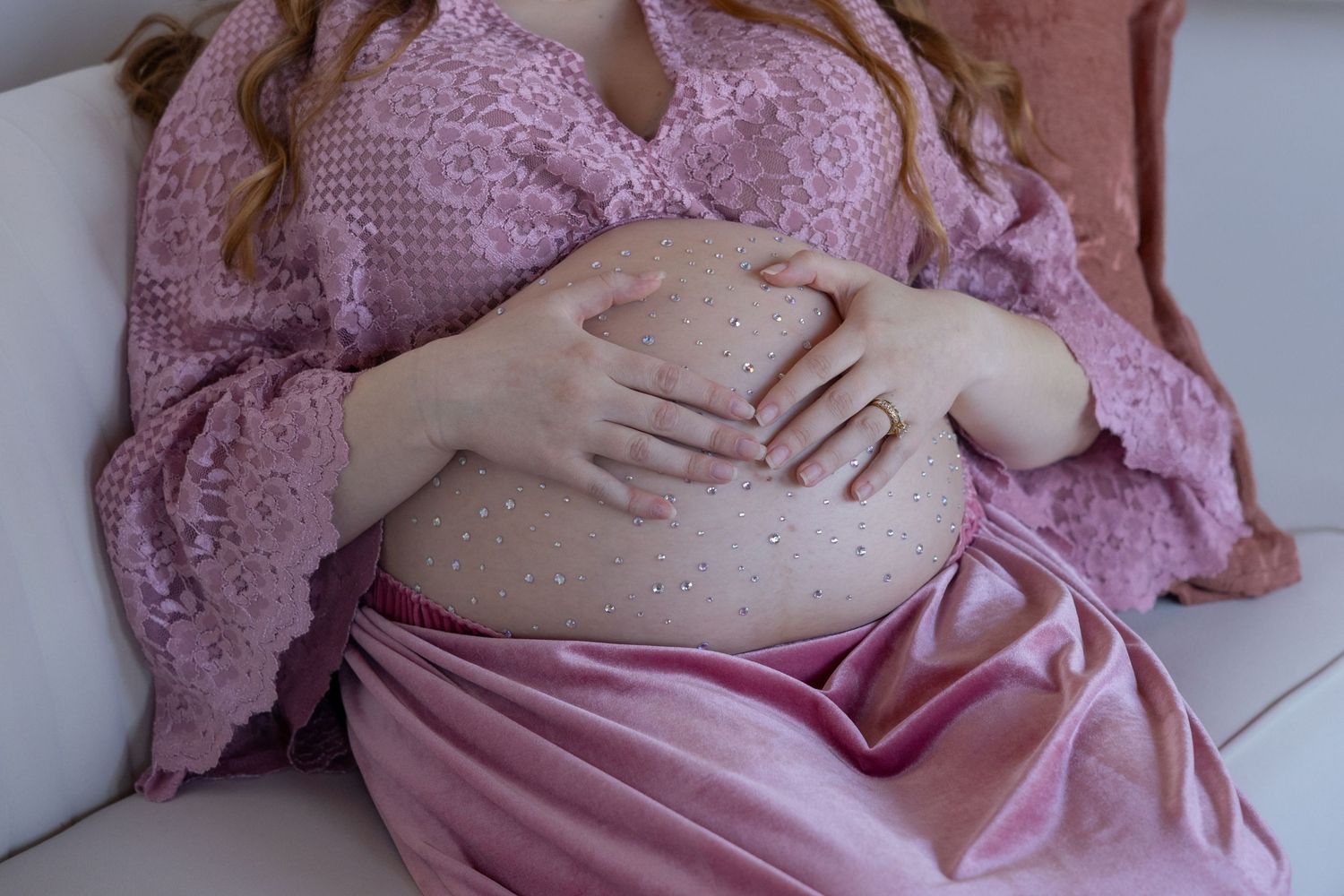 Intimate maternity photography session featuring soft pink lace details.