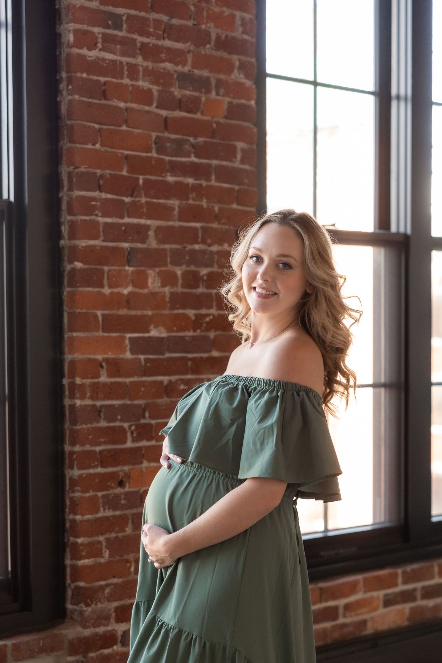 Artistic portrait session in brick-walled studio with natural window lighting.