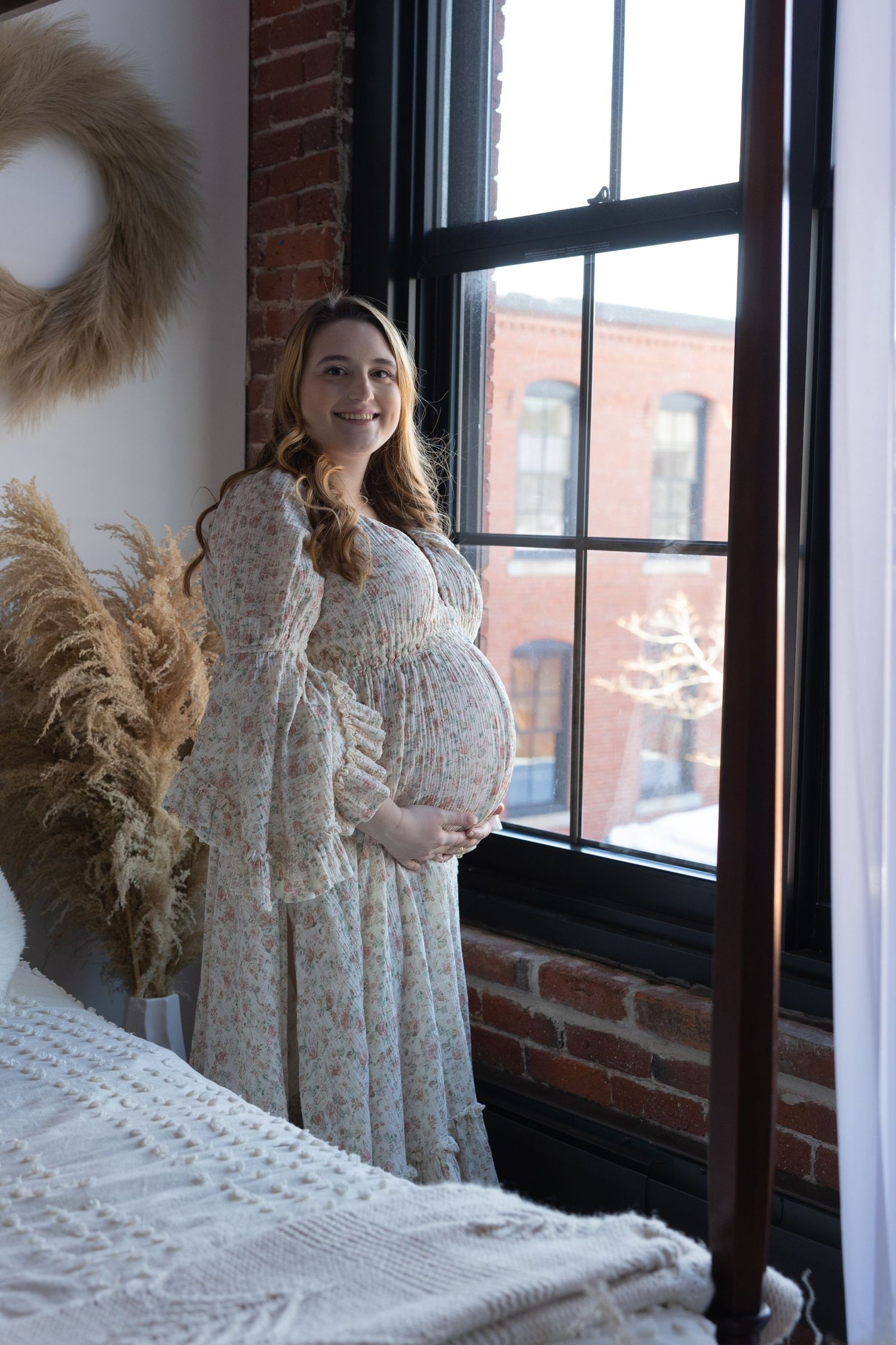 Artistic portrait series by window featuring cream lace dress and dried pampas grass decor.