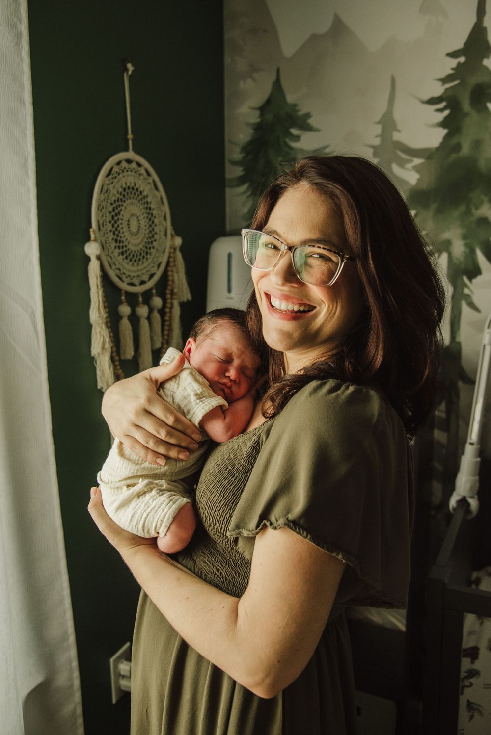 A heartwarming series of photos showing tender moments between parent and newborn in a woodland-themed nursery.