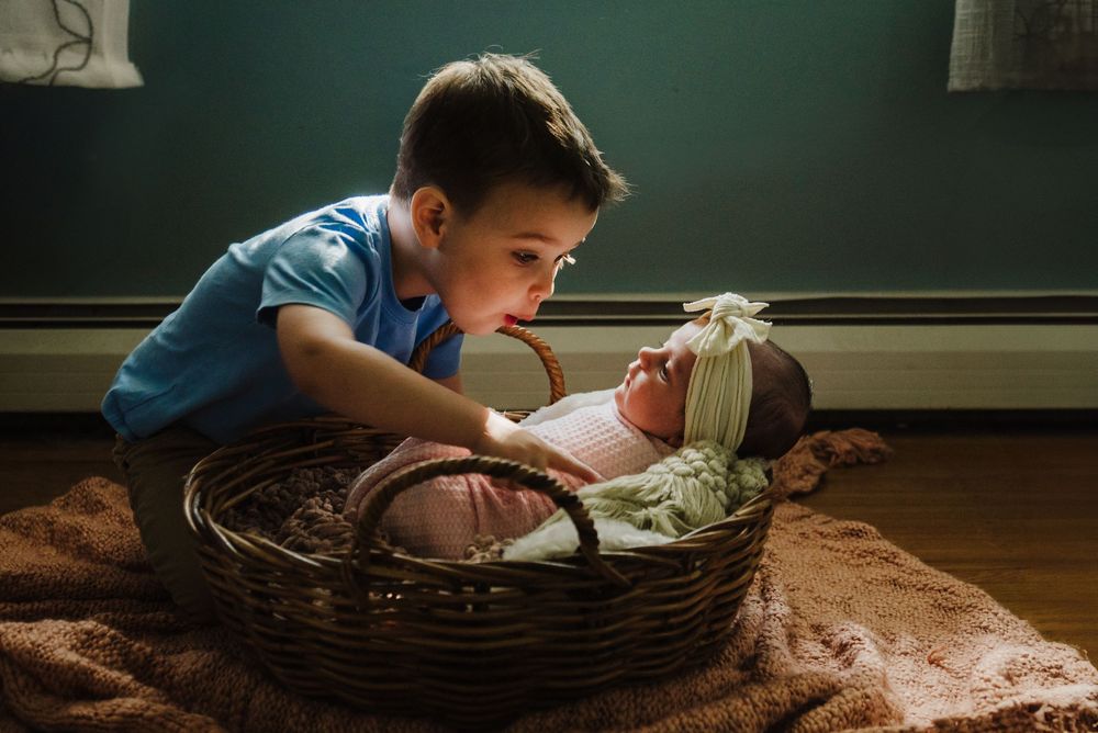 A child in a wicker basket reads a book by flashlight in a darkened room creating a cozy atmosphere.