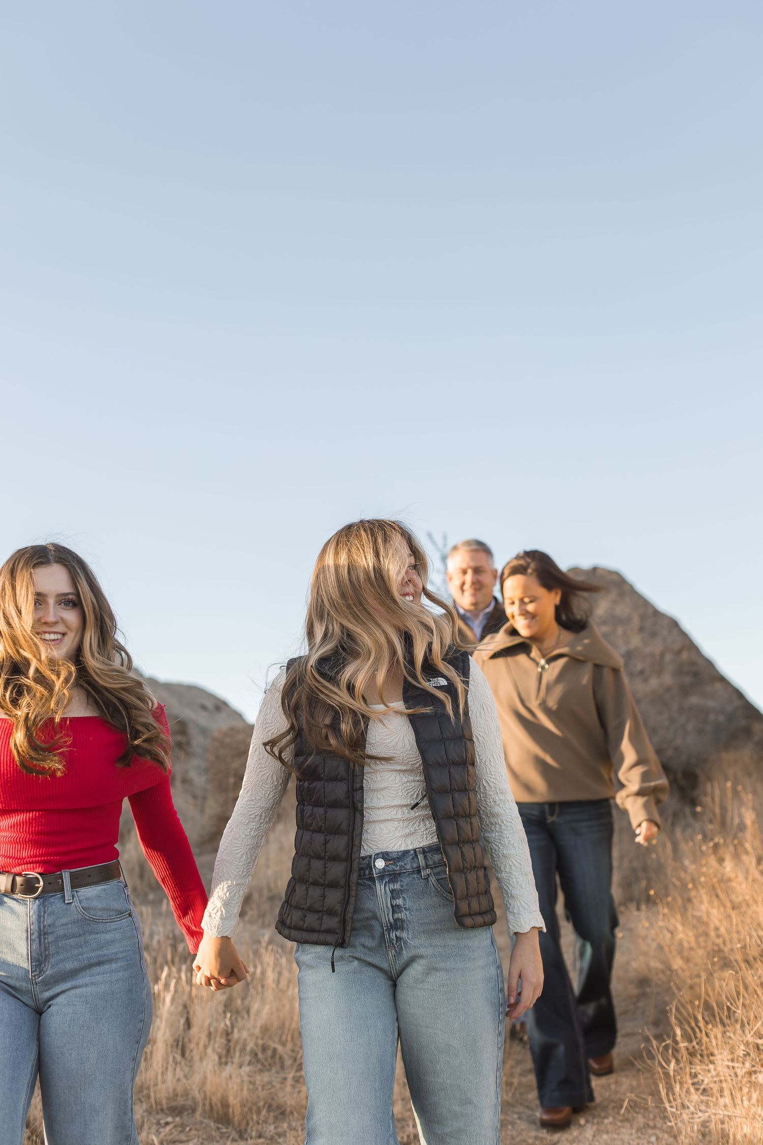 A group of people in casual attire stand together against a mountain backdrop during golden hour.