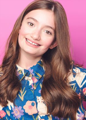 Portrait series on pink background featuring floral blue top and wavy brown hair styling.