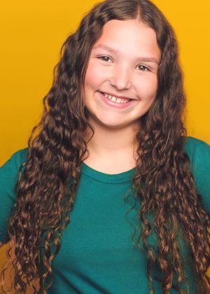 Child wearing green shirt poses against vibrant yellow background showing different expressions and angles.