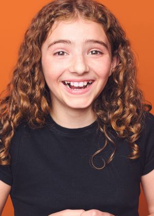 Child with curly hair wearing black shirt poses against orange background in series of expressive portraits.