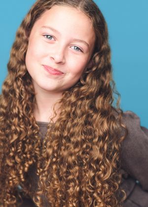 Close-up portraits showing long curly honey-brown hair against blue backdrop.