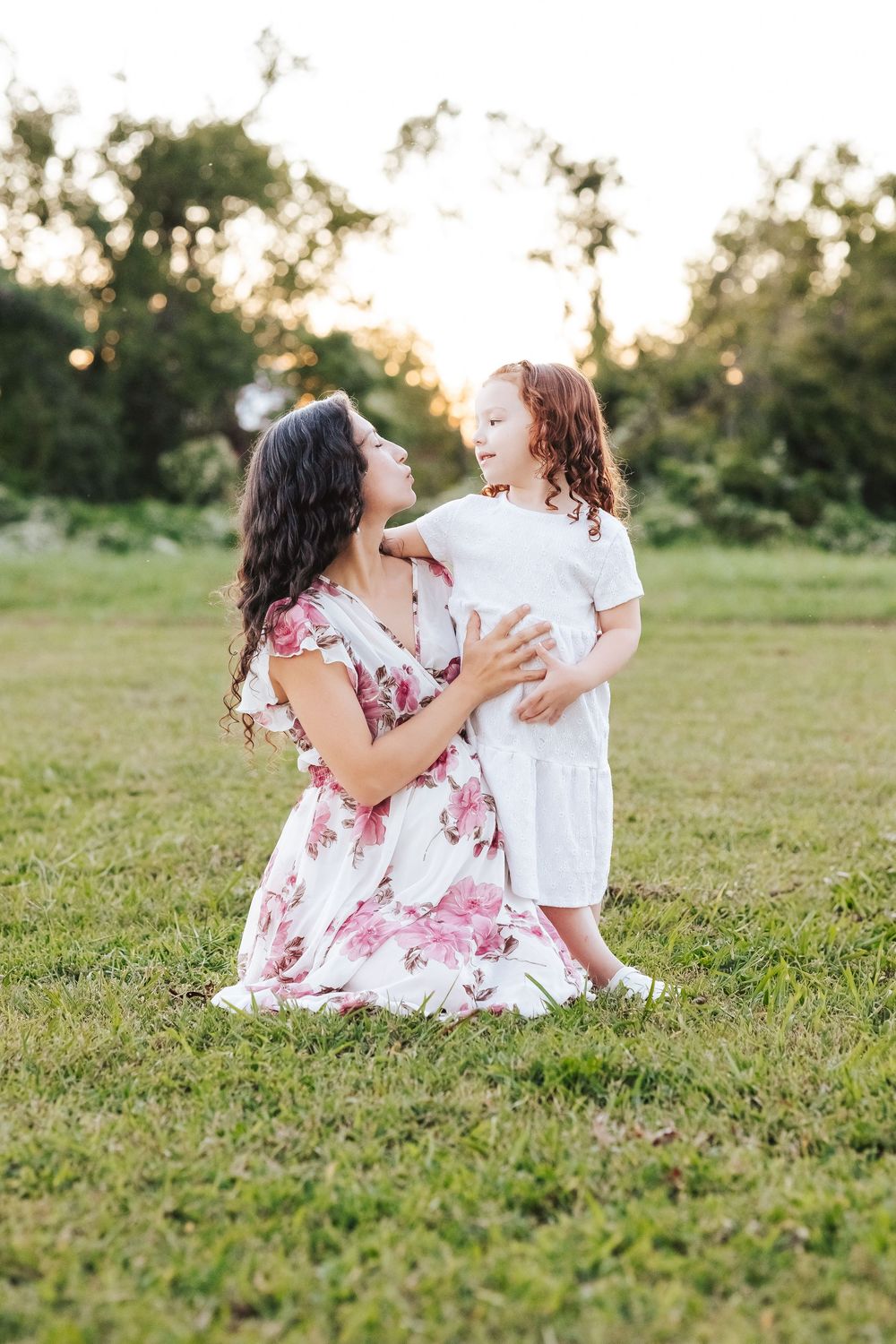 Parent and child playing together on green grass during a summer evening.