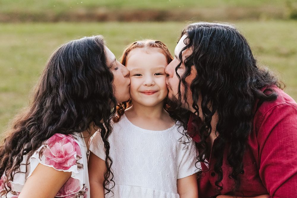 Family sharing loving moments together outdoors in casual attire.