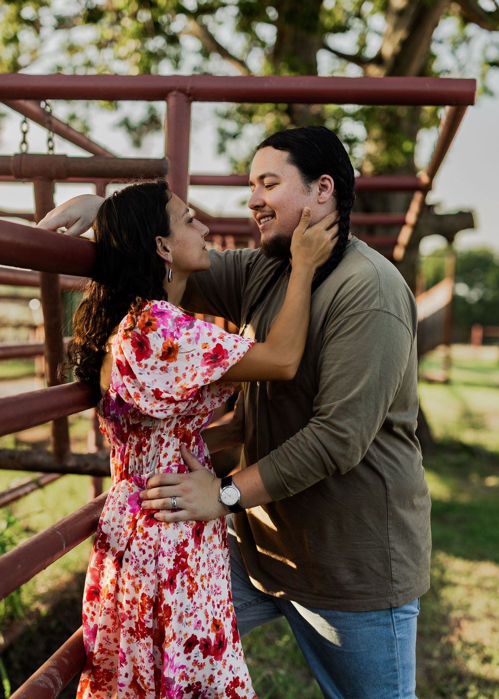 A couple shares playful moments near rustic farm equipment at sunset.