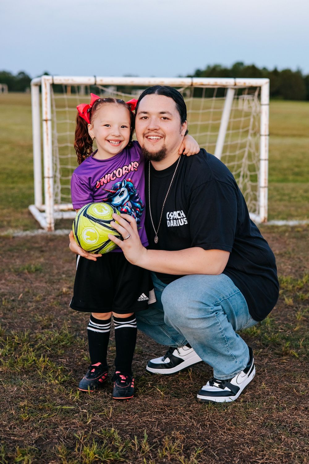 Soccer themed family photo session on field with goal posts in background.