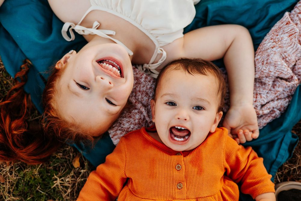 Candid moments captured on blue and white bedding with bright orange accents.
