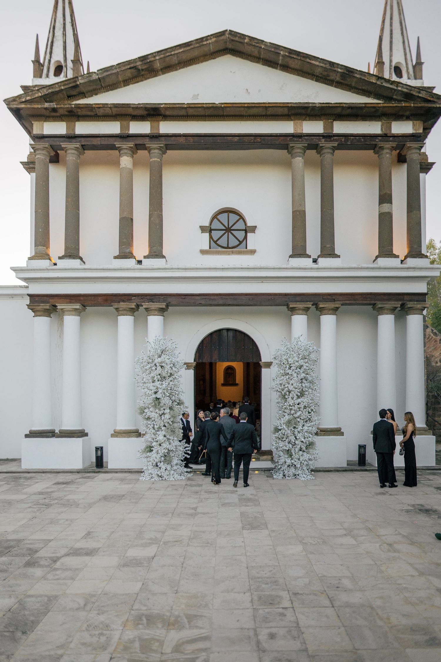Sequence of wedding venue entrance photos showing white walls, stone columns and decorative floral arrangements.