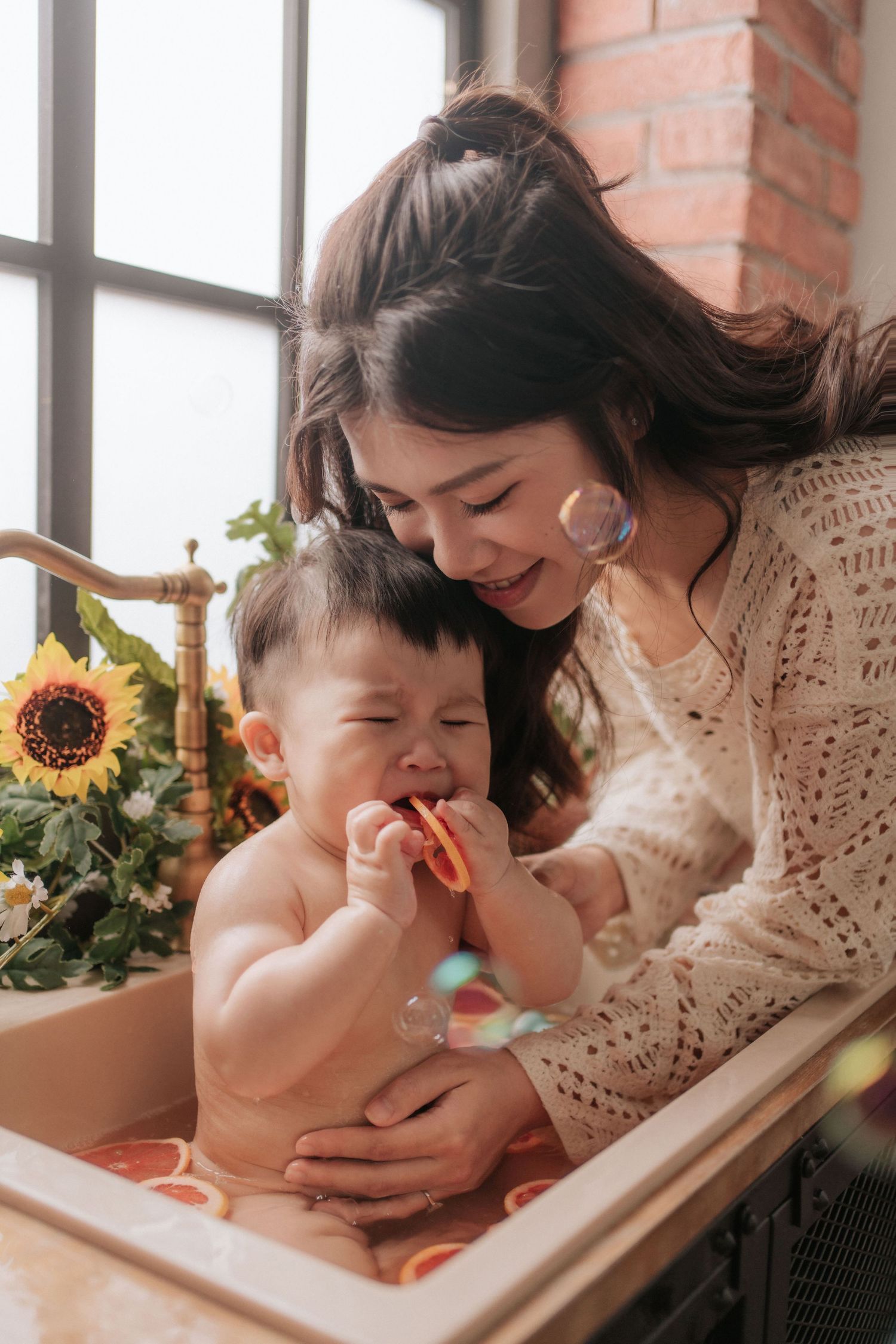 A tender moment shared between parent and child during bath time with sunflowers decorating the bathroom window.