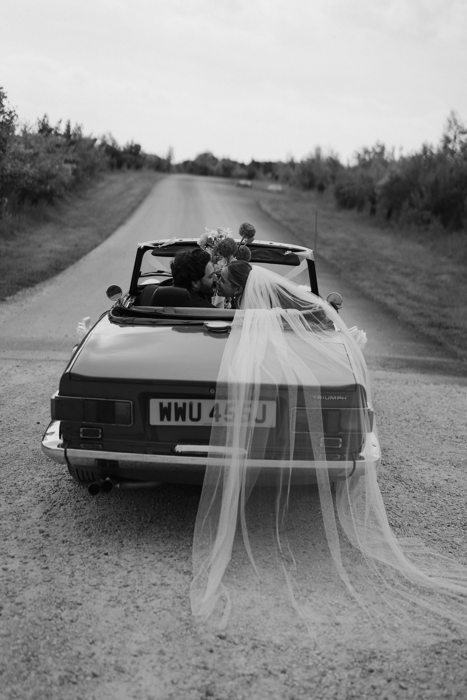bride and groom kissing in car at old gore in cotswolds