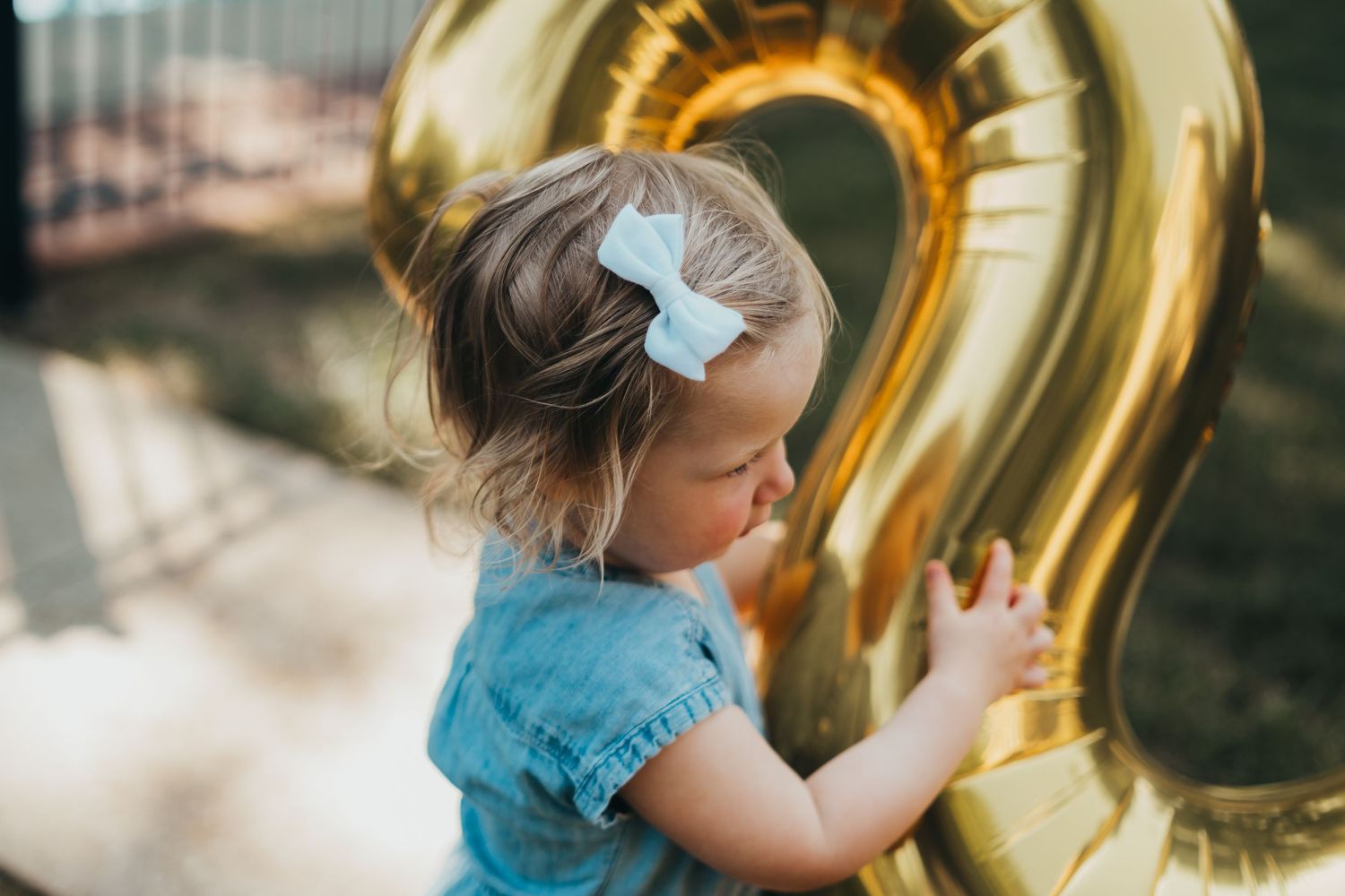 Child playing with large gold number balloon decorations.